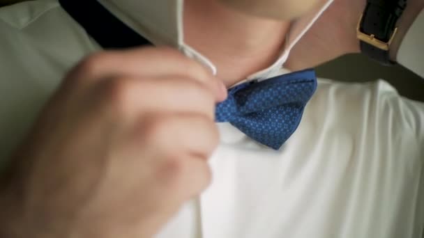 A close-up shot of a man straightening his tux. Clip. Close-up of a man in a tux straightening his bowtie, two hands, no jacket. The man straightens his tie - Footage, Video