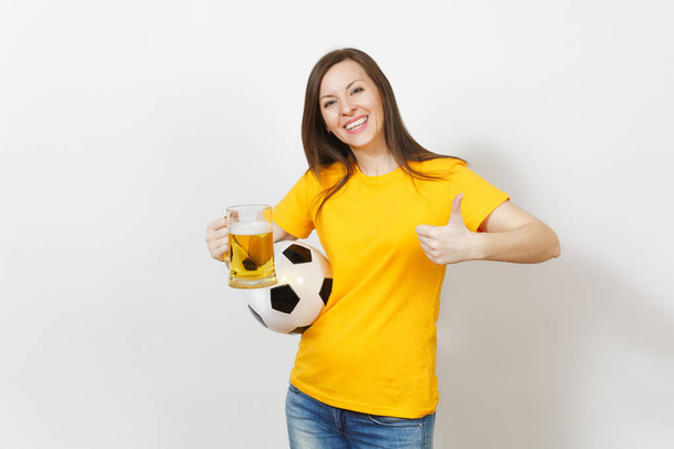 Beautiful European young cheerful woman, football fan or player in yellow uniform holding pint mug of beer, soccer ball isolated on white background. Sport, play football, healthy lifestyle concept. - Fotoğraf, Görsel