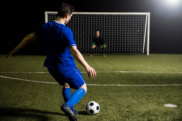 Young soccer player taking a penalty kick against a blurred goalkeeper in the goal - Photo, Image