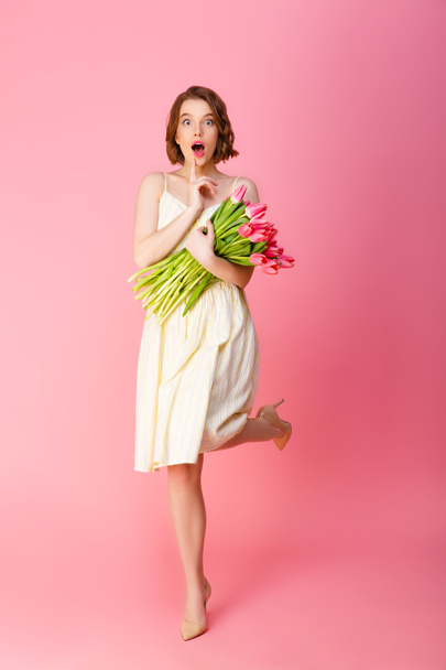 young shocked woman with bouquet of pink tulips isolated on pink - Zdjęcie, obraz