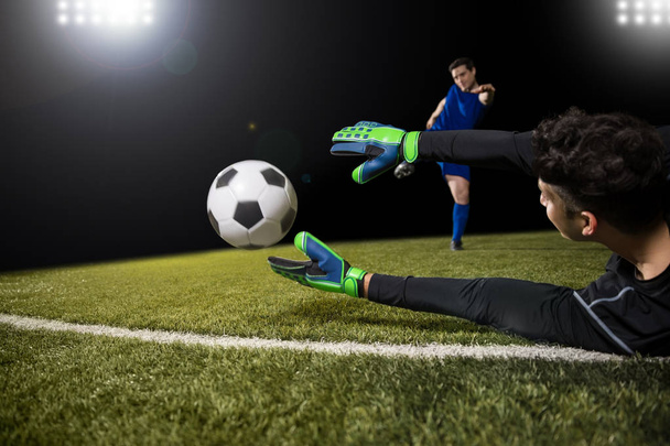 Футболист удар мяч и вратарь пытаются поймать мяч и сохранить цель
 - Фото, изображение