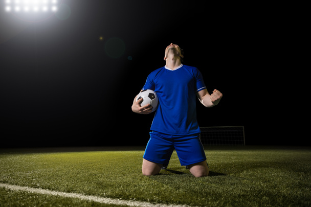 Fotbalista útočník v modrém týmu slaví gól na stadionu během utkání - Fotografie, Obrázek