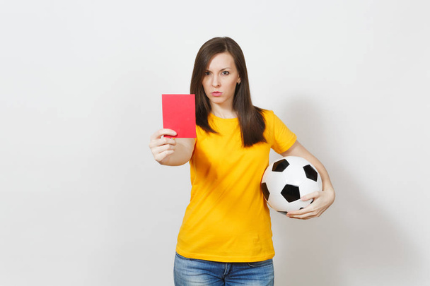 Европейская серьезная молодая женщина, футбольный судья или игрок в жёлтой форме, показывающий красную карточку, держа футбольный мяч изолированным на белом фоне. Спорт, футбол, концепция здорового образа жизни
. - Фото, изображение