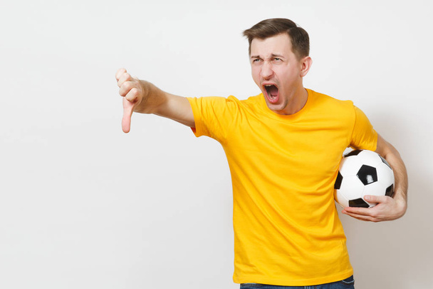 Inspirado joven europeo hombre, ventilador o jugador en uniforme amarillo sostienen pelota de fútbol, animar equipo de fútbol favorito, expresivo gesticular manos aisladas sobre fondo blanco. Concepto de estilo de vida. Copiar espacio
. - Foto, imagen