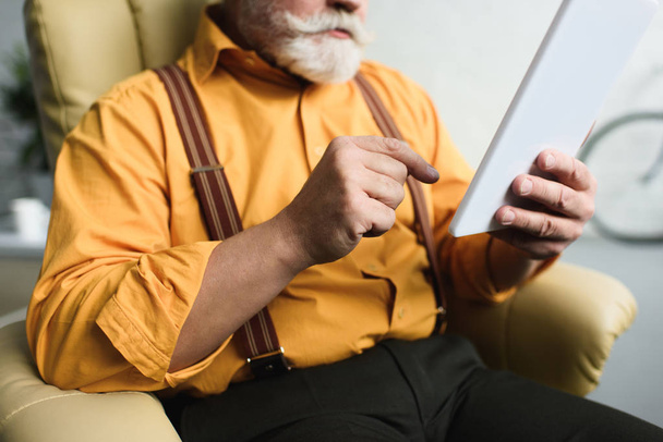 colpo ritagliato di uomo anziano barbuto utilizzando tablet digitale a casa
 - Foto, immagini