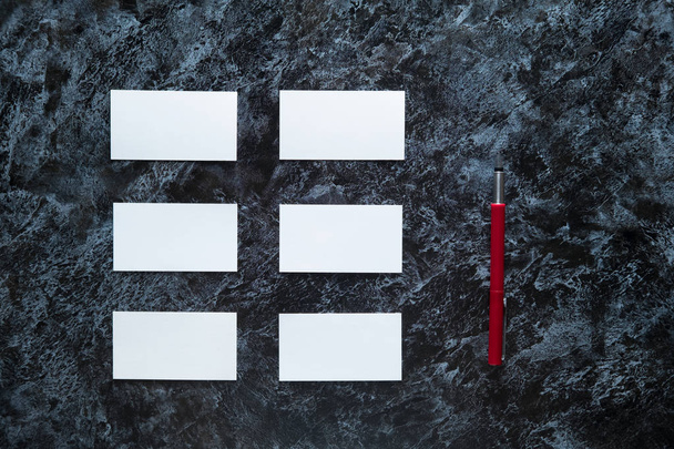 few clean white business cards with space for text and a red fountain pen on a dark marble surface - Фото, зображення