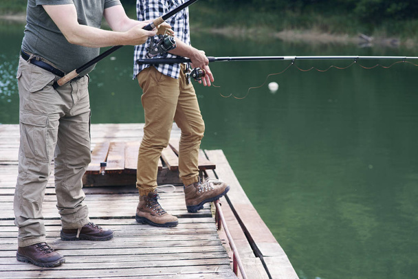 Homens irreconhecíveis com pesca vara
  - Foto, Imagem