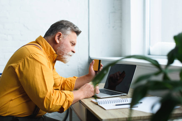 bearded senior man holding credit card and using laptop at home - Foto, Imagem