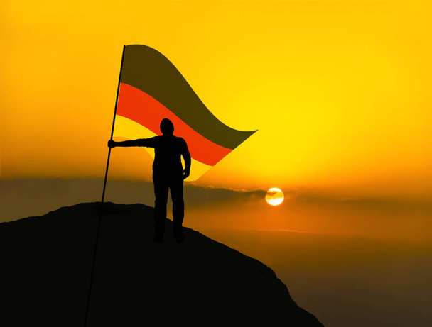 silhueta homem vencedor acenando bandeira alemanha no topo do pico da montanha
 - Foto, Imagem