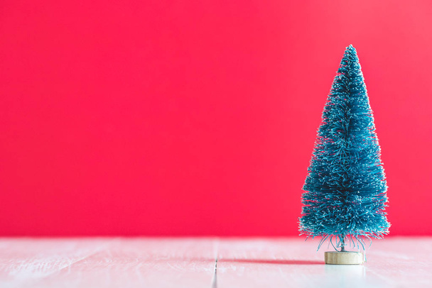 green  artificial pine tree on red background - Foto, Imagen