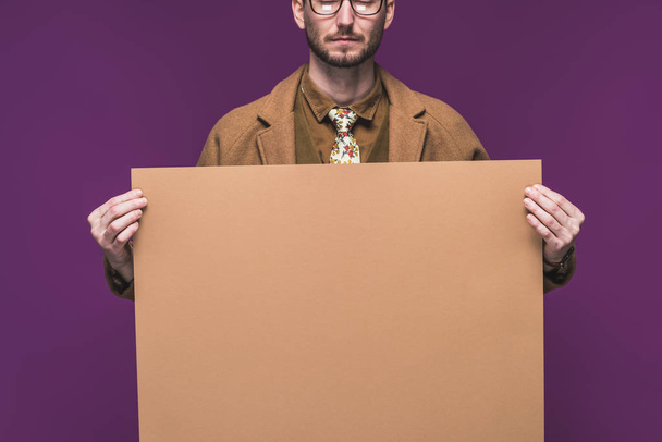 Stylish man in vintage styled clothes holding empty paper isolated on purple - Photo, Image