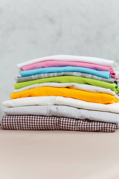 Close up pile of ironing colorful clothes, washed laundry, family clothing on ironing board isolated on white background. Housekeeping concept. Copy space for advertisement. With place for text. - Photo, Image