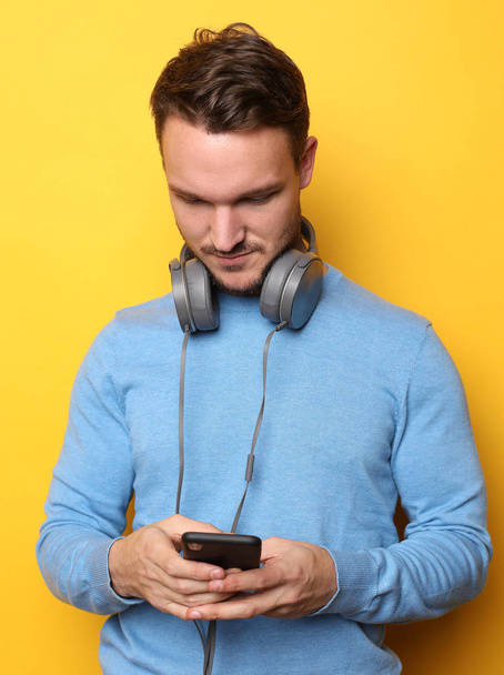Handsome Man lictening to music over yellow background - Photo, image
