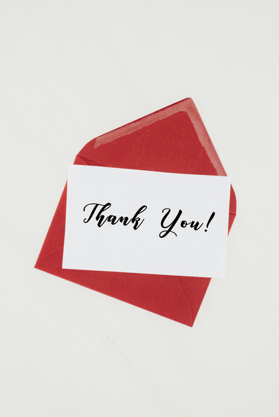 top view of red envelope with THANK YOU lettering on paper isolated on white - Photo, Image
