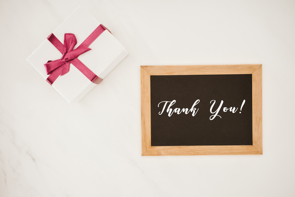 top view of blackboard in frame with THANK YOU lettering and gift box isolated on white - Foto, afbeelding