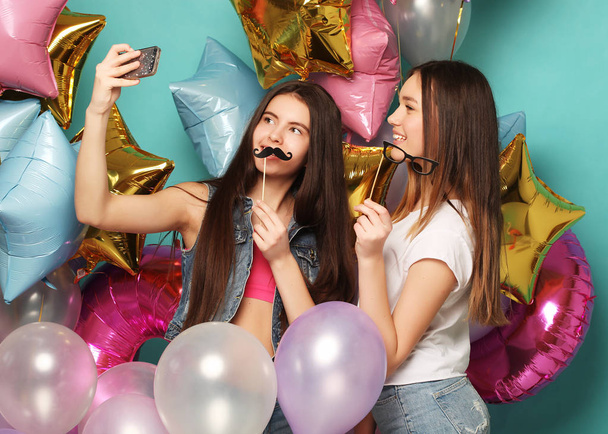 Two   girls friends with colorfoul  balloons make selfie on a ph - Foto, imagen