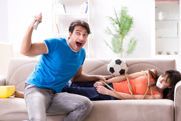 Мужчина связывает свою жену, чтобы смотреть спортивный футбол - Фото, изображение