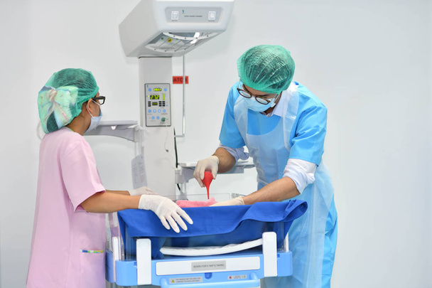  Ázsiai férfi szülész és nővér külön-külön megvizsgálják a kórház újszülött - Fotó, kép