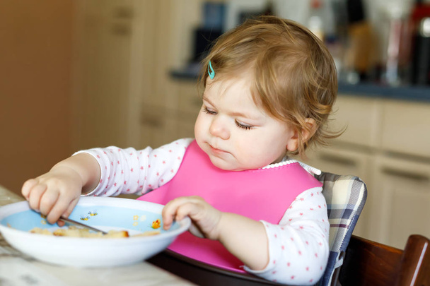 Entzückendes kleines Mädchen, das aus einem Löffel püriertem Gemüse und Püree isst. Ernährungs-, Kinder-, Ernährungs- und Personenkonzept - Foto, Bild