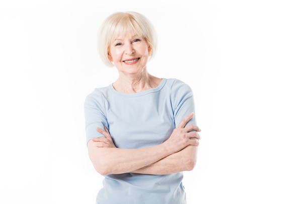 Femme âgée souriante debout avec les bras croisés isolés sur blanc
 - Photo, image