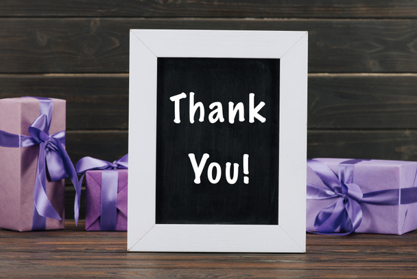 thank you lettering on chalkboard in frame with gift boxes against wooden wall - Foto, Bild