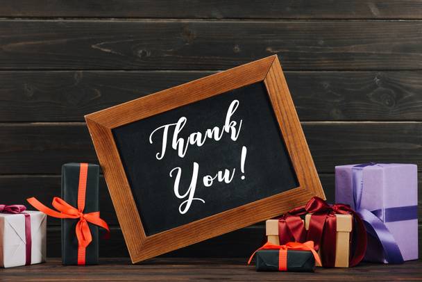 thank you lettering on chalkboard in frame with various gift boxes against wooden wall - Photo, Image