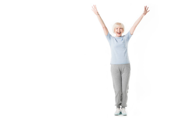 Glückliche Seniorin steht mit erhobenen Armen auf weißem Grund - Foto, Bild