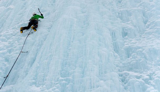 férfi ice hegymászó a meredek és fagyasztott vízesés mély télen az Alpokban - Fotó, kép