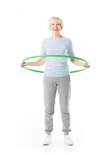 Smiling enior sportswoman doing hula hoop exercise isolated on white - Fotó, kép