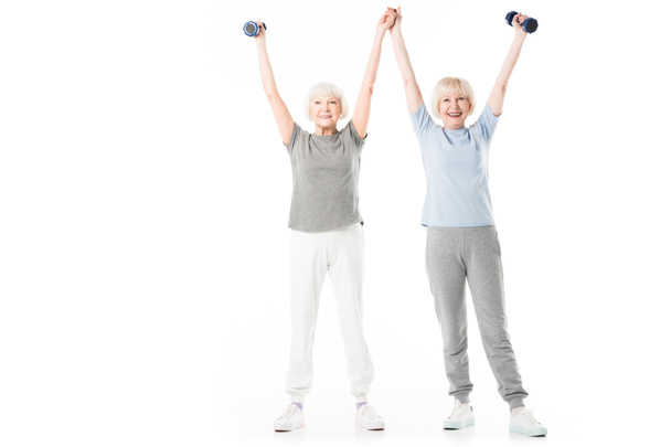 Senior sportswomen with arms up holding dumbbell isolated on white - Zdjęcie, obraz