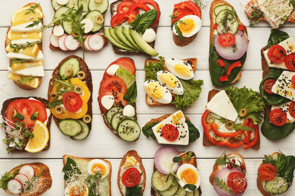 Variété de sandwichs végétariens sains sur bois blanc, vue de dessus
 - Photo, image