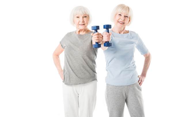 Two senior sportswomen doing exercise with dumbbell isolated on white - Photo, Image