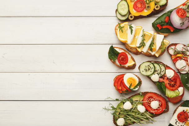 Scala aan gezonde vegetarische broodjes op wit hout, top uitzicht - Foto, afbeelding
