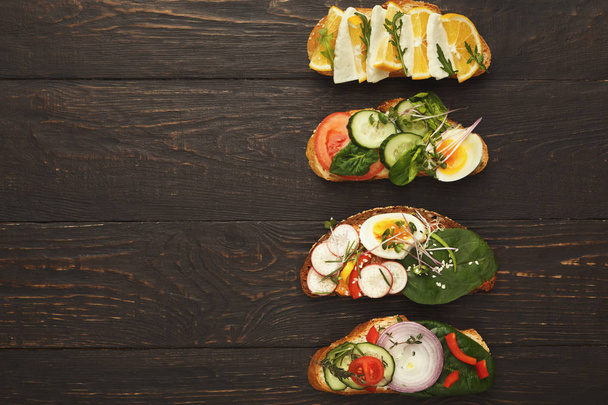 Scala aan gezonde vegetarische broodjes op donker hout, top uitzicht - Foto, afbeelding