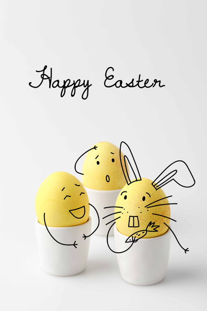 három sárga festett húsvéti tojás tojás áll képregény rajzolt arca fehér - Fotó, kép