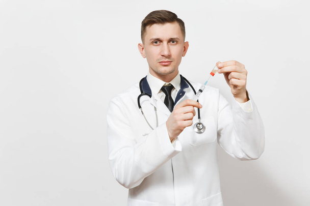 Vážný mladý lékař muž izolovaných na bílém pozadí. Lékař v uniformě zdravotní stetoskop kreslí tekutého léku z láhve s injekční stříkačkou s jehlou. Zdravotnický personál, medicína koncepce. - Fotografie, Obrázek
