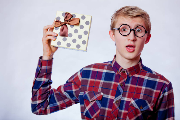 Young nerd teen boy with eyeglasses and gift box on white background  - Foto, Bild