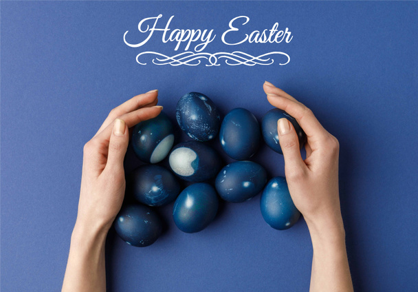cropped image of woman touching blue painted easter eggs with happy easter lettering - Foto, Imagem