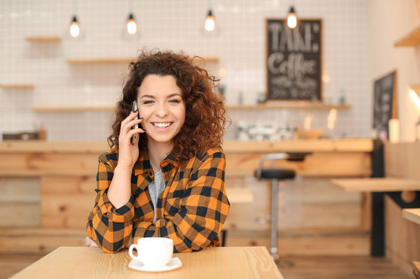 Young woman talking on mobile phone indoors - Photo, Image