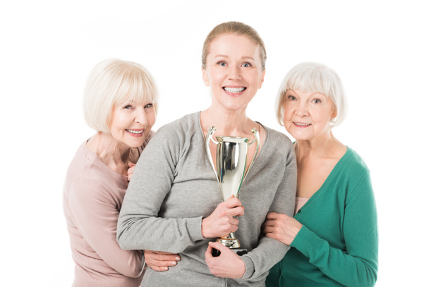 Mujeres elegantes sonrientes celebrando con trofeo aislado en blanco
 - Foto, imagen