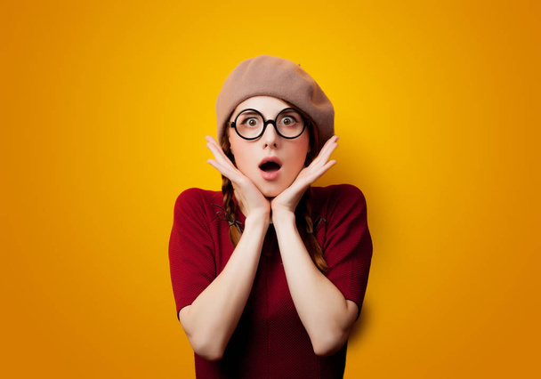 Portrait of redhead girl with eyeglasses and beret on yellow background  - Photo, Image