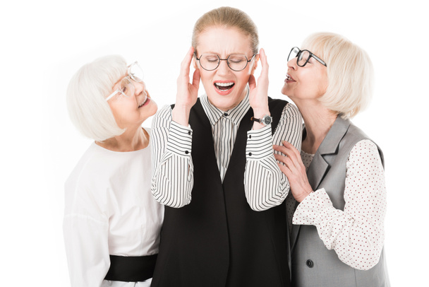 Madura elegante mujer de negocios cerrando oídos entre dos mujeres de negocios senior en gafas aisladas en blanco
 - Foto, Imagen