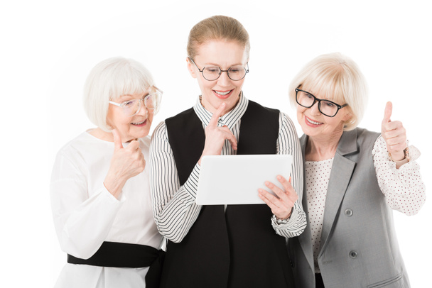 Three stylish businesswomen in eyeglasses looking at digital tablet isolated on white - Foto, Bild