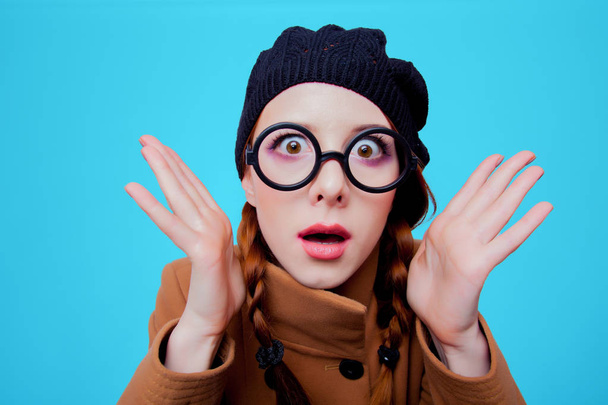Retrato de uma jovem ruiva engraçado nerd menina com óculos e casaco no fundo azul
  - Foto, Imagem