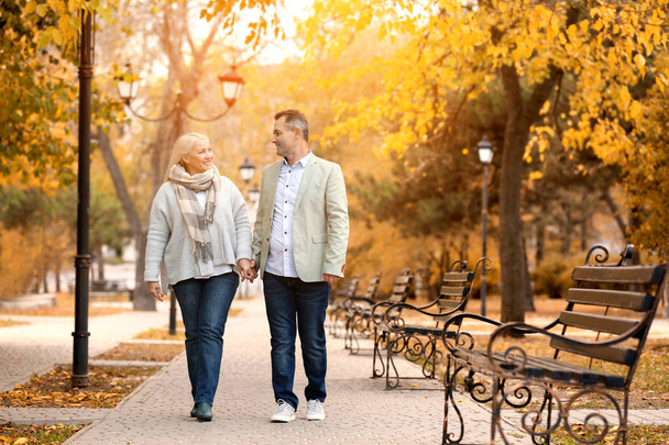 Beautiful mature couple walking in autumn park - Foto, Imagen
