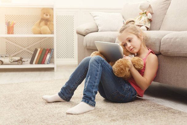 Meisje met Tablet PC- en teddy bear thuis - Foto, afbeelding