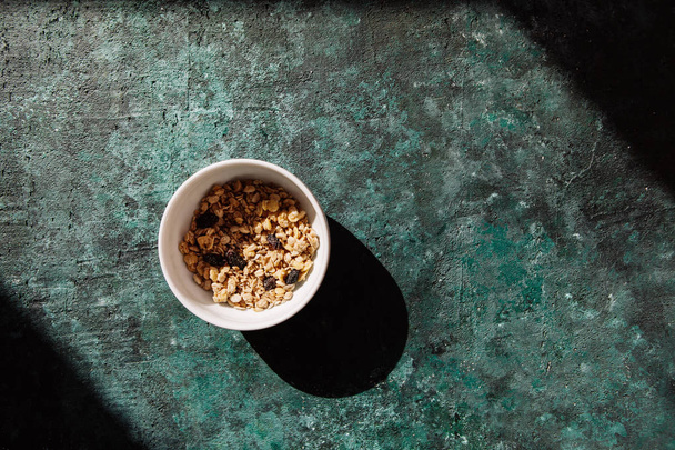 prato com muesli cozido no forno, granola com bagas em um fundo de concreto verde
 - Foto, Imagem