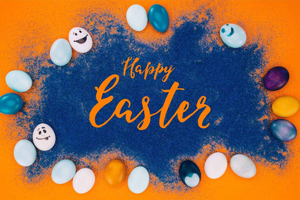 felülnézet Boldog húsvéti betűkkel kék homok és a húsvéti tojás a narancs felület - Fotó, kép