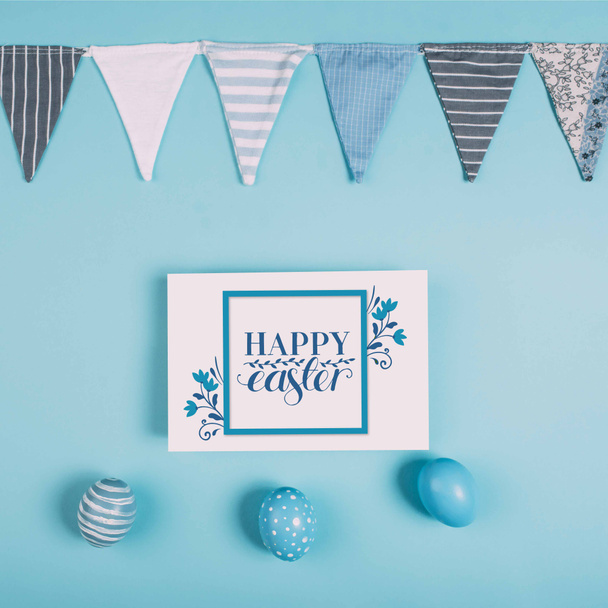 Mutlu Paskalya yazı ve Paskalya ile tebrik kartı üstten görünüm mavi yüzey üzerinde yumurta - Fotoğraf, Görsel