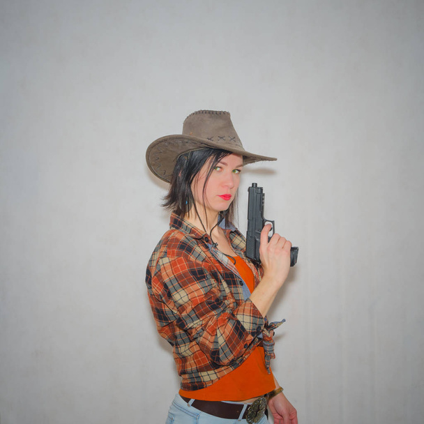 a girl the cowboy with pistol on the grey background - 写真・画像